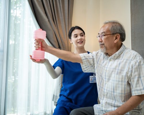 Caregiver Asian Therapist woman serve physical therapy for older patient exercise with dumbbell